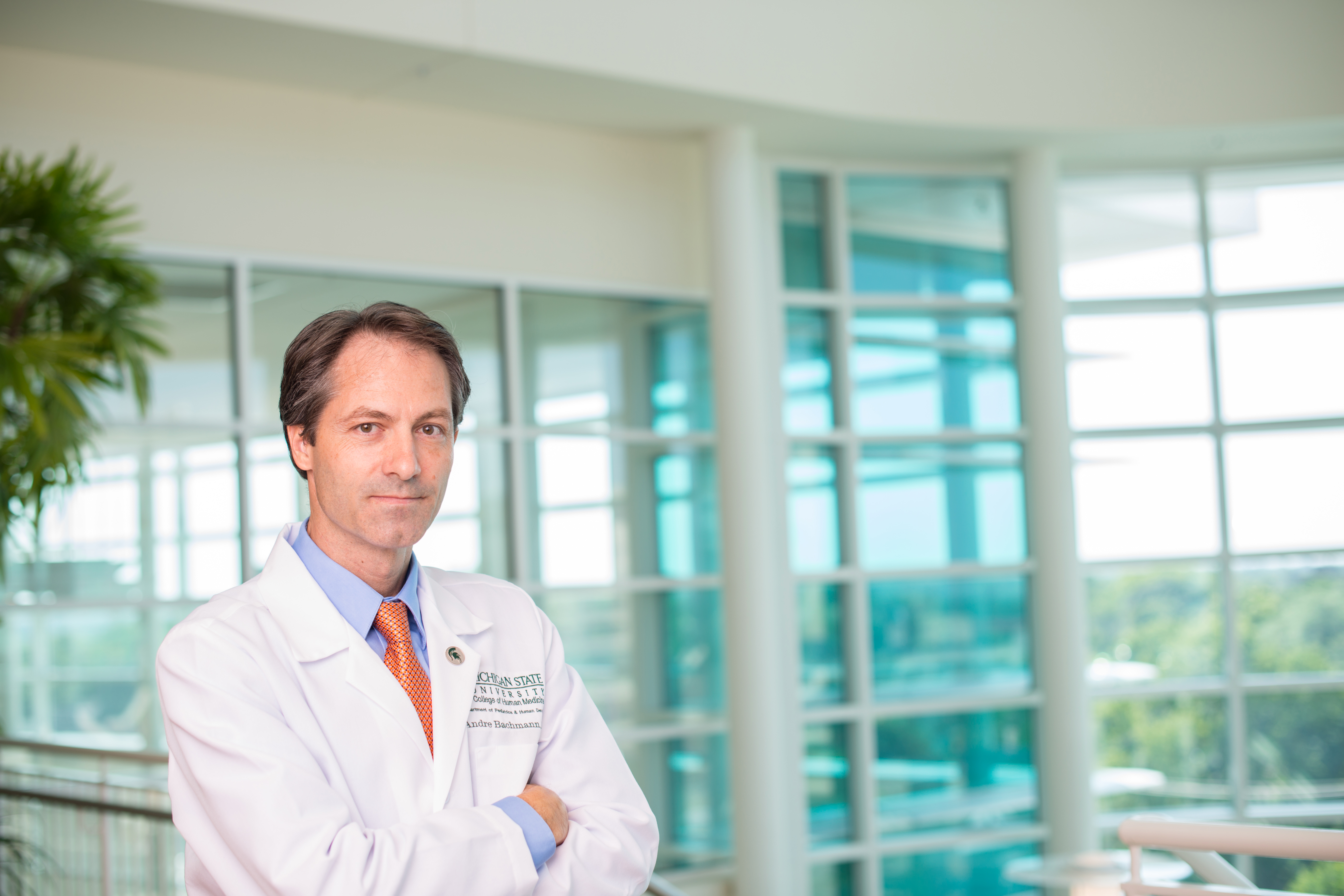 Professor and Associate Chair for Research with the MSU College of Human Medicine Department of Pediatrics and Human Development, André S. Bachmann, PhD, dressed in his lab attire and posed in the atrium of the Secchia Center in Grand Rapids, MI